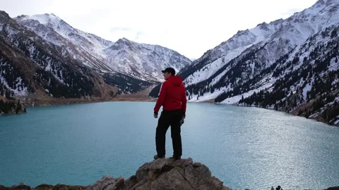 The guy is standing on a rock overlooking the lake Video stock 229606250