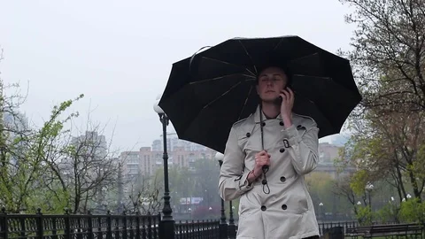 The guy is standing under the umbrella and talking on the phone Video stock 74853325