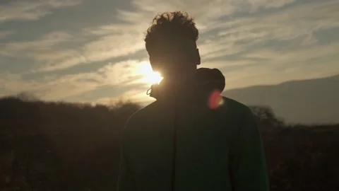 The guy stands against the background of the rising sun in the mountains Stock Footage 171946204