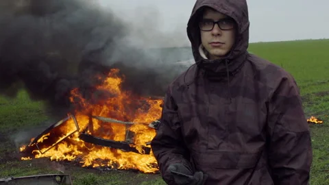 A guy stands on the background of a burning car, slow motion Video stock 95189186