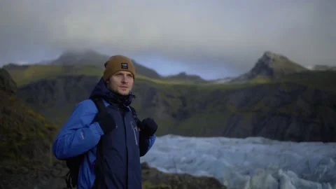 The guy stands on a background of mountains and a glacier Stock Footage 130470392