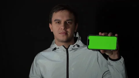 The guy stands on a black background in a reflective jacket with a mobile phone Stock Footage 150787700