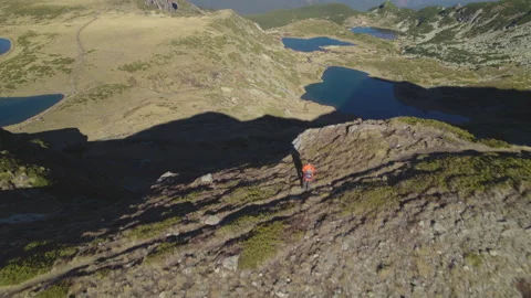 Guy stands on a cliff and admires the view of Seven Rila Lakes Stock Footage 220842013