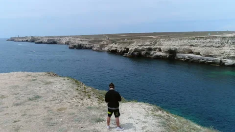 Guy stands on the edge of a mountain and manages a drone Stock-Footage 103084757