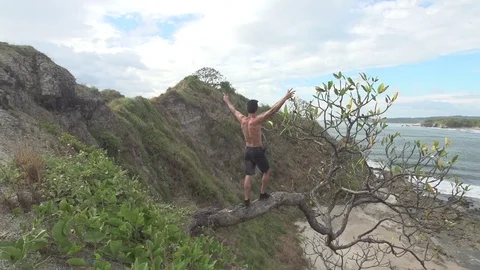 Guy Stands on Frangipani Tree Looking Over Beach Adventure Stock Footage 85130954