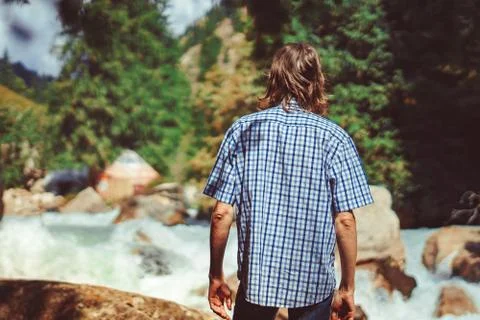 The guy stands at the mountain river Stock Photos