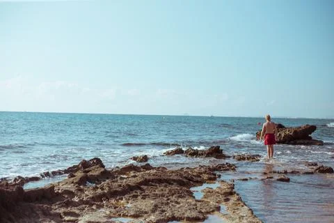 The guy stands on the rocks by the sea Stock Photos