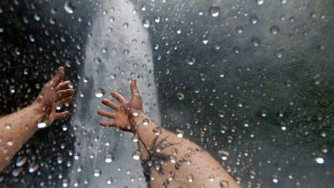 A guy stands under a large waterfall in Bali Stock Footage 125994059