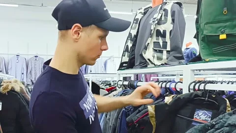 The guy in the store chooses clothes Stock Footage 194518962