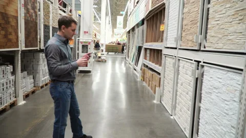 Guy at store of construction materials choosing wall covering for renovation 4k Stock Footage 88134346