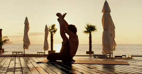 The guy stretched his leg up and does a stretch during a yoga class on the Stock Footage 249606469