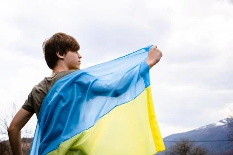 The guy stretched the Ukrainian flag against the background of the sky. Stock Photos
