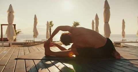 The guy is stretching and doing stretching on a sunny beach in the morning Stock Footage 249235081