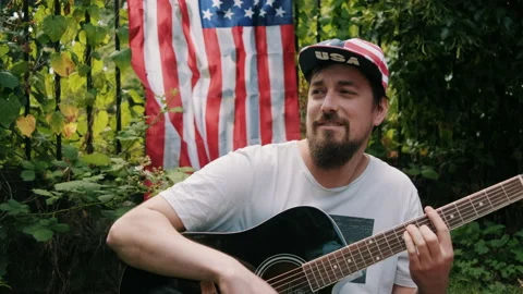 Guy strumming guitar for independence day Stock Footage 133614767