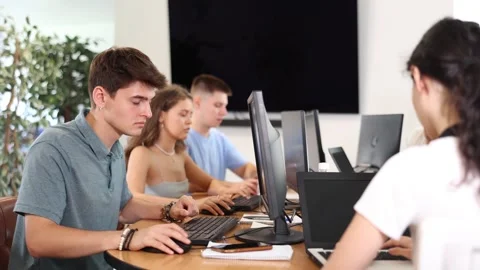 Guy student of computer courses looks at monitor screen, types on keyboard and Stock Footage 275004309