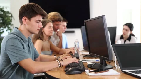 Guy student of computer courses looks at monitor screen, types on keyboard and Stock Footage 310965618