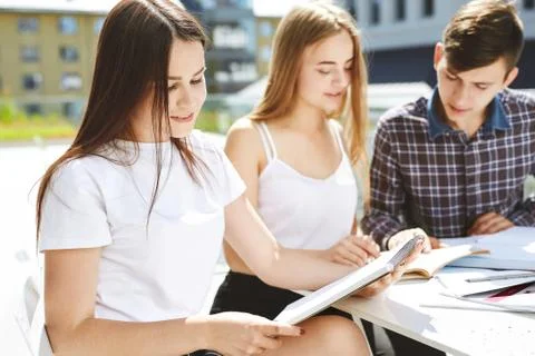 Guy student explains to the girls something and shows in a notebook Free Stock Photos
