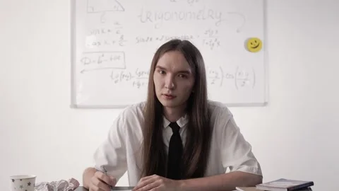 Guy student with long brown hair sits at his desk during a lesson Stock-Footage 264511552