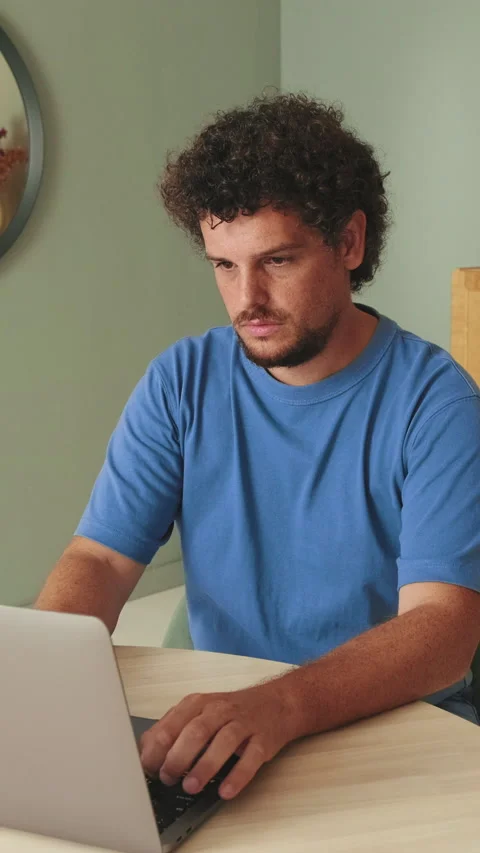 Guy student uses laptop while sitting in the living room at the table Video stock 252501890