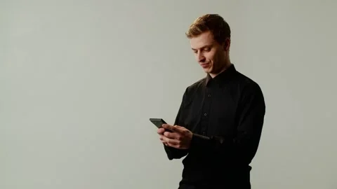 A guy student uses a smartphone, in cheerful mood messages with friend and Stock Footage 253624771