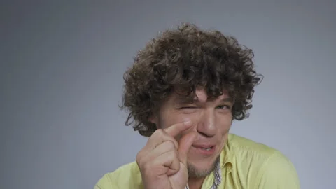Guy in the studio shows a small size gesture. Curly man shows off small size Stock Footage 142212901