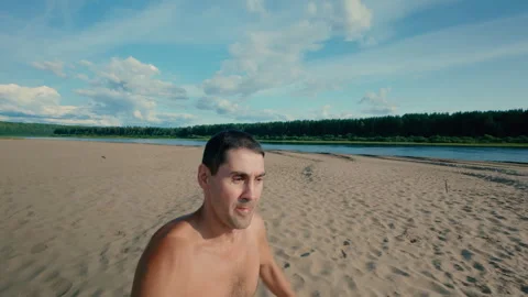 A guy stumbles while jogging on the beach and falls face first into the sand. Stock Footage 314668157