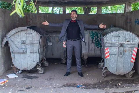 Guy in a suit and bowtie posing in front of trash bins Stock Photos