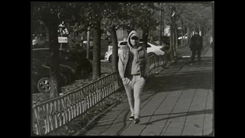 The guy in the suit and hat walks down the sidewalk with iPods in their ears Video stock 70847232