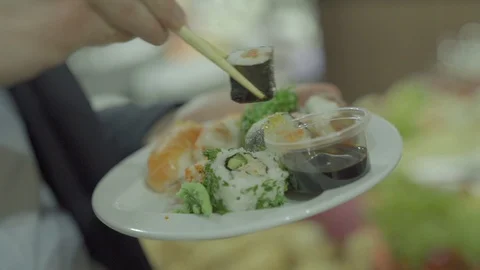 Guy in suit eats sushi using chopsticks Stock Footage 111381362