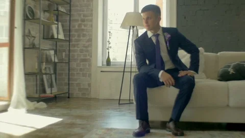 Guy in the suit is sitting on the couch and looking away Stock Footage 81397265