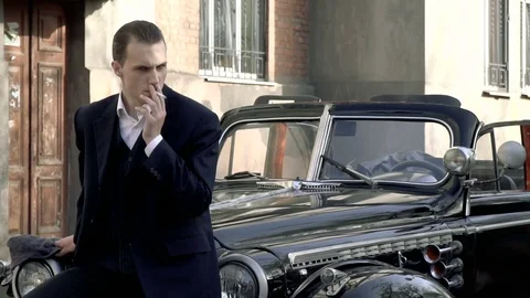 A guy in a suit smokes sitting on a retro car Vidéo 75515295