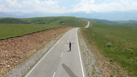 Guy in summer in black clothes descends from the mountain on a skateboard Video stock 136399990