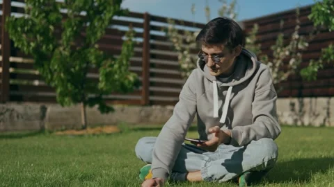 A guy in sunglasses sits, tears grass and inhales the aroma of freshly cut grass Stock Footage 247966909