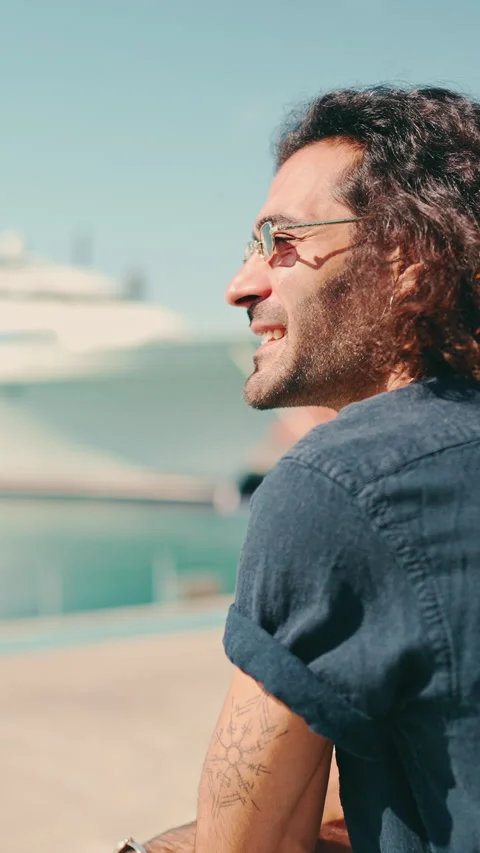 Guy in sunglasses stands in harbor and looks at ships and yachts Video stock 226949667