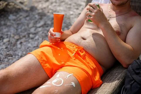 Guy with sunscreen on his leg Stock-Fotos