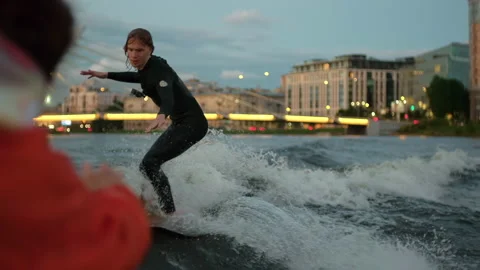A guy on a surfboardrolls on the waves of the city channel in slow motion Stock Footage 205610417