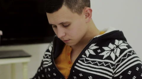 Guy in a sweater reading a book sitting on a chair Stock Footage 56425972