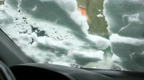 The guy sweeps the snow from the snow-covered car window Vídeo Stock 68646394