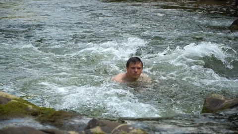 The guy is swimming in the river. A young cute guy bathes in a clean mountain Stock Footage 95283607