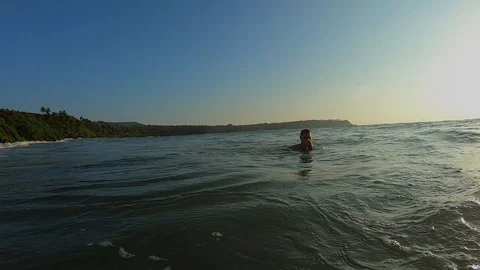 Guy is swimming towards the wave in a day before sunset Vídeos de archivo 129754538