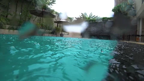A guy swims in the hotel pool in the tropical rain Video stock 247238701