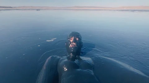 A guy swims in a mud lake on his back. Therapeutic mud. Stock Footage 316838517