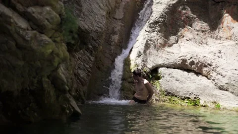 The guy swims under the waterfall in the Old Bar Montenegro Stock Footage 196125463