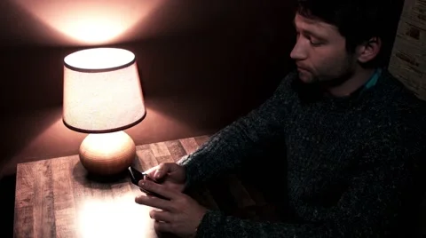 The guy at the table plays on the smartphone Stock Footage 56240765