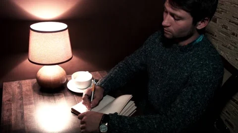 The guy at the table writing in a notebook and drinking coffee Video stock 56250853