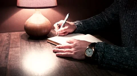 The guy at the table writing in a notebook pen Stock Footage 56240796