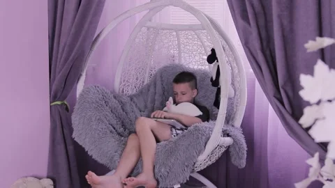 Guy with a tablet playing while sitting in a rocking chair at home Stock Footage 198726843