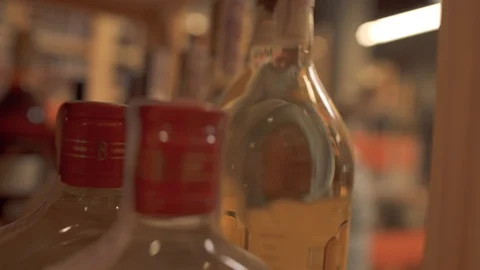 Guy taking a bottle of alcoholic beverage from a wooden shelf in liquor store Stock Footage 99385215