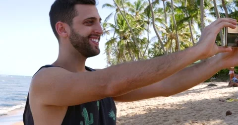 Guy taking a selfie in a tropical beach Stock Footage 62840431