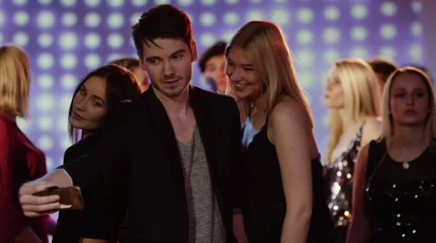 Guy taking a selfie with two girls on dancefloor at club Stock Footage 61647477